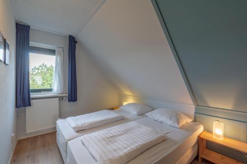 a bedroom with a white bed with a window at Villa Duynopgangh 46 Julianadorp aan Zee in Julianadorp