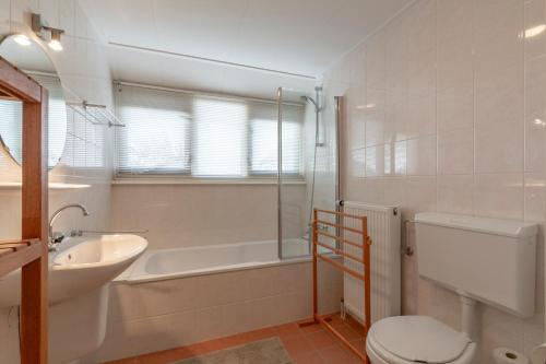 a bathroom with a sink and a toilet and a bath tub at Villa Duynopgangh 46 Julianadorp aan Zee in Julianadorp