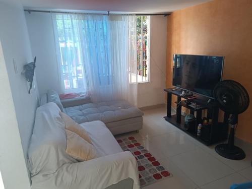 sala de estar con sofá blanco y TV en HABITACION PARA DOS PERSONAS en Barranquilla