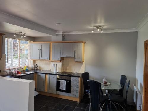 a kitchen with white cabinets and a table with chairs at Modern Apartment good distance from Dublin City and Airport 4people in Dublin