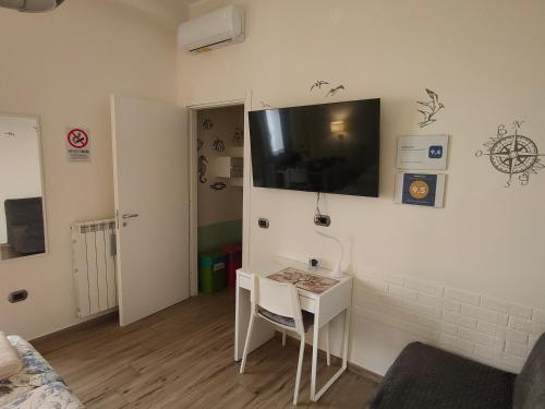 Zimmer mit einem Tisch und einem TV an der Wand in der Unterkunft Blue Rose Private Room in Salerno