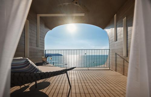 a room with a balcony with a view of the ocean at PARKROYAL Langkawi Resort in Pantai Cenang
