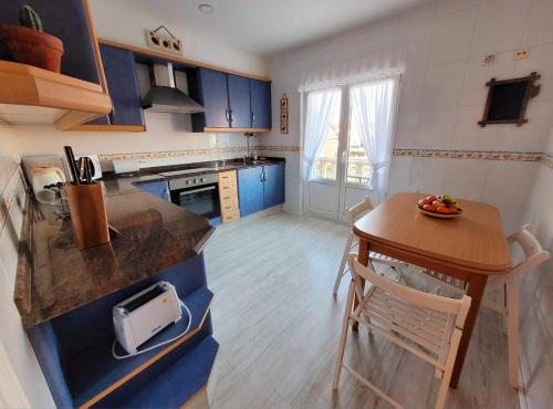a kitchen with blue cabinets and a small table with a bowl on it at Camiño á praia in Fisterra