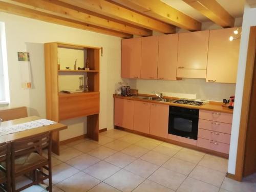 une cuisine avec des placards en bois, une table et un comptoir dans l'établissement Appartamento Dimaro Folgarida Daolasa ski, à Monclassico