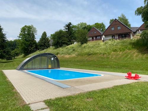 een zwembad met een kas naast een huis bij Vila 66 - Čistá v Krkonoších in Cerny Dul