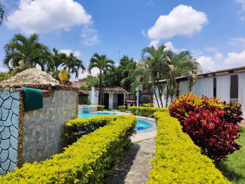 um jardim com flores amarelas e uma piscina em Melao Hostel Campestre y Vivero em Palmira