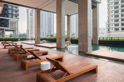 吉隆坡的住宿－Arcoris Soho 2bedroom 1-7pax Industrial Loft Style，一座带木制椅子和水的游泳池的建筑