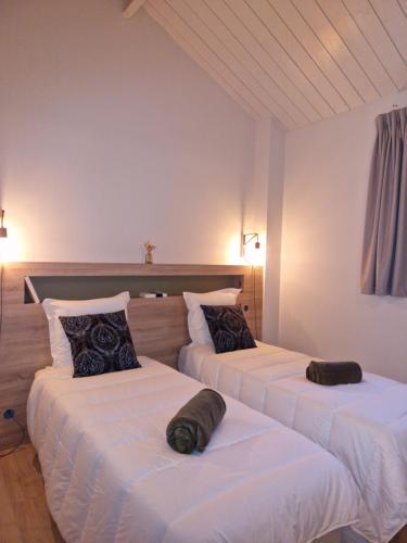 2 łóżka w pokoju z białą pościelą i poduszkami w obiekcie Gîte de l’Etabli w mieście Cellettes