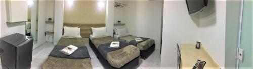 Habitación con 2 camas y mesa. en Hotel Malka, en São Paulo
