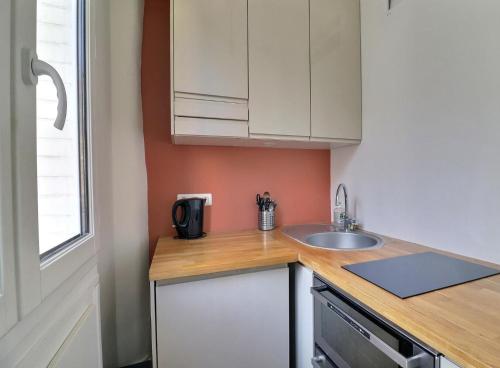 une petite cuisine avec un évier et un comptoir dans l'établissement Sweet and cosy apartment near the Eiffel Tower, Roland Garros & PSG Stadium, à Paris
