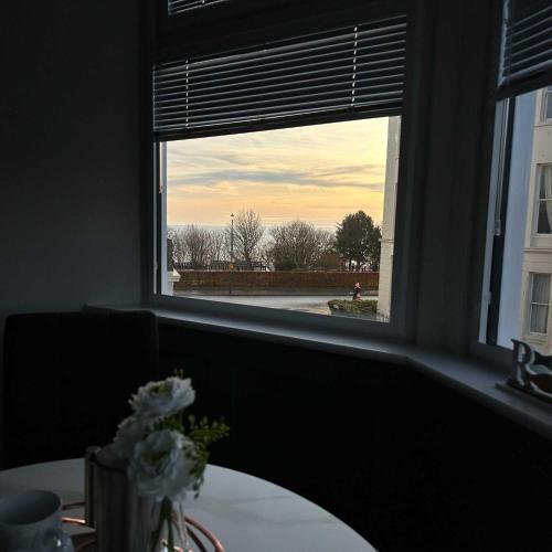 a window with a table and a vase of flowers at Brooklands Filey Seaside Retreat Flat 4 in Filey