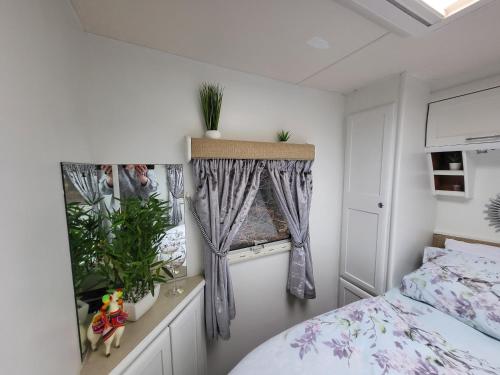a bedroom with a bed and a window with plants at Glamping with Llamas in Wisbech
