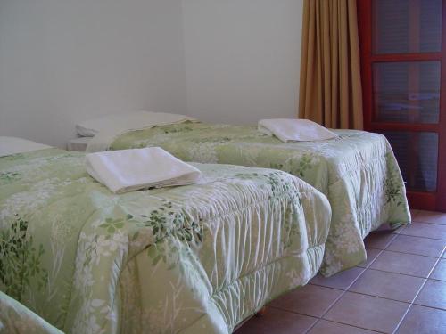 two beds with green and white covers in a room at Pousada Rural Paraíso in Águas de São Pedro