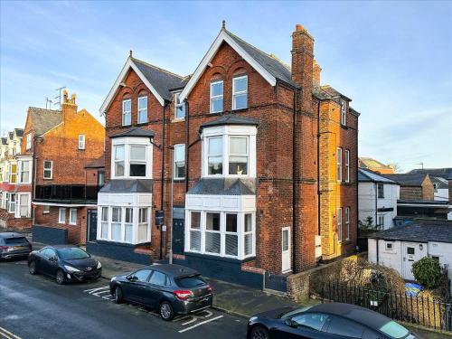 a large brick house with cars parked in front of it at Brooklands Filey Seaside Retreat Flat 6 in Filey