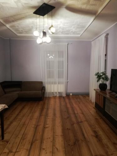 an empty living room with a couch and wooden floors at Pils ielas apartamenti in Kandava