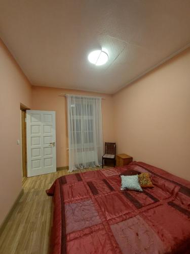 a bedroom with a large bed with a red blanket at Pils ielas apartamenti in Kandava