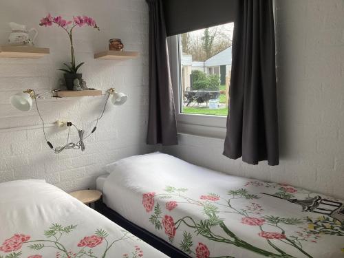 Zimmer mit 2 Betten und einem Fenster mit Blumen in der Unterkunft Casa della nonna bungalow 2 in Simpelveld
