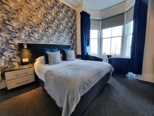 a bedroom with a large bed with blue curtains at Hen Dy in Llandudno
