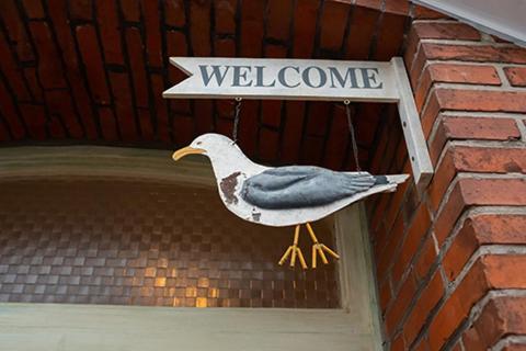a bird hanging from a door with a welcome sign at Aparthotel Domizil in Borkum