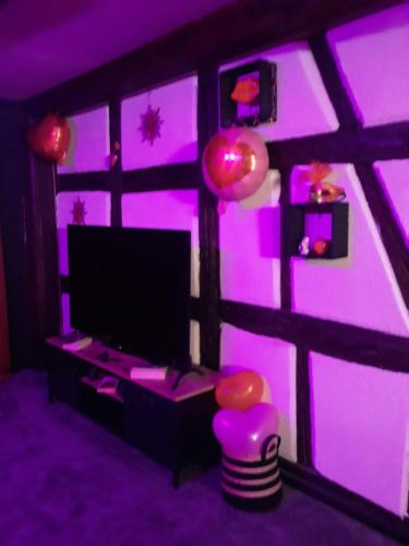 a living room with a purple room with a tv at LOVE ROOM Le rouge et noir in Barr