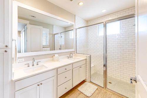 a white bathroom with two sinks and a shower at Dolphin View in Rockport