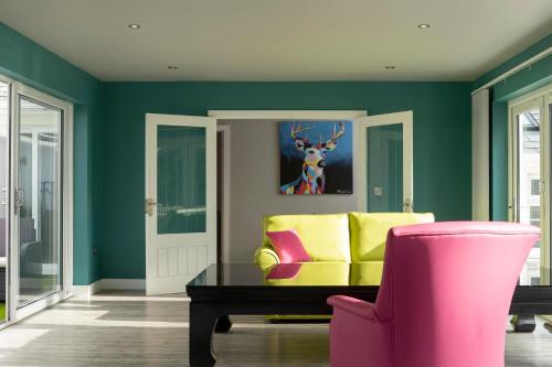 a green living room with a yellow couch and a pink chair at Talland Bay Hotel, Looe in Talland