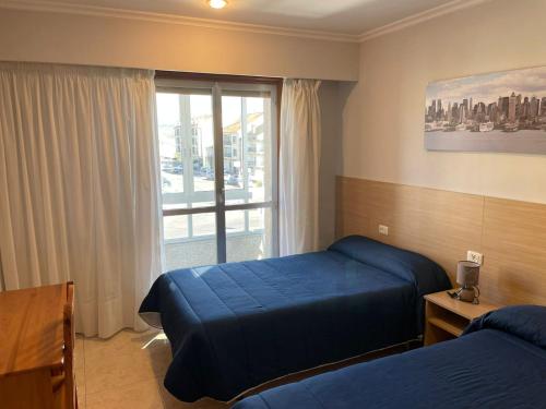 um quarto de hotel com duas camas e uma janela em HOSTAL CID em Ourense