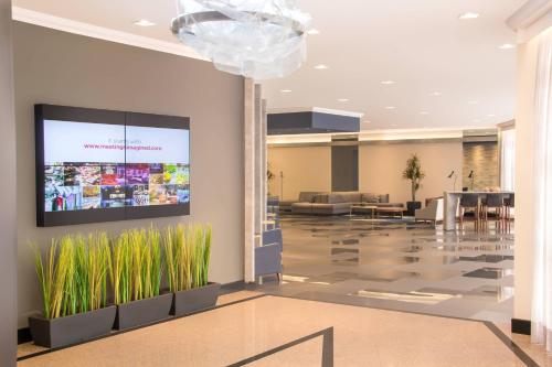 a lobby with a tv on the wall with plants at Marriott São Paulo Airport Hotel in Guarulhos