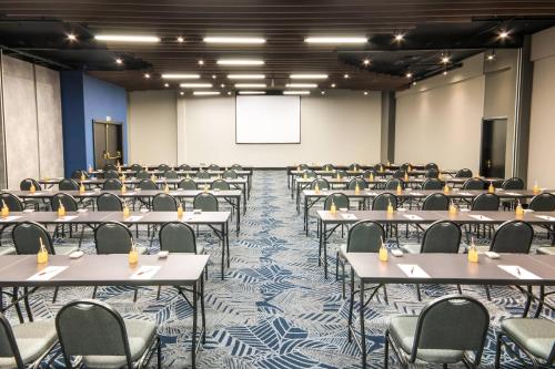 an empty room with tables and chairs and a projection screen at Marriott São Paulo Airport Hotel in Guarulhos