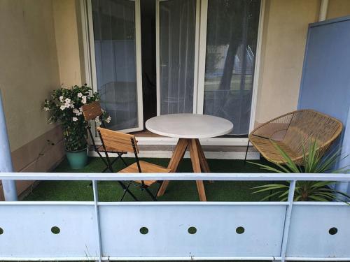 - un balcon avec une table et deux chaises sur une terrasse couverte dans l'établissement Mignon appartement en résidence avec piscine, à Biscarrosse
