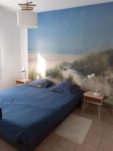 - une chambre dotée d'un lit bleu et d'une fresque murale représentant la plage dans l'établissement Mignon appartement en résidence avec piscine, à Biscarrosse