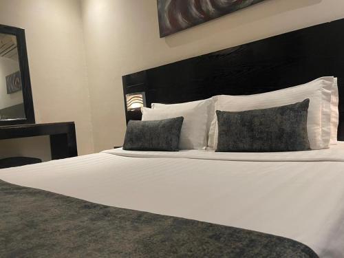 a bedroom with a white bed with two pillows at Nawara Hotel Khanshalila in Riyadh