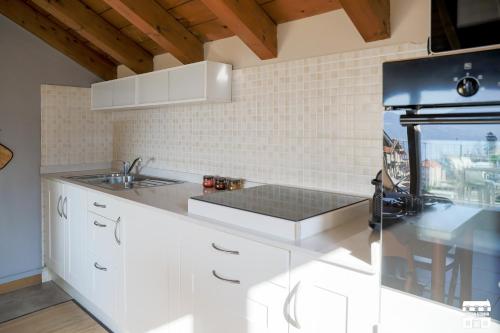 a kitchen with white cabinets and a black refrigerator at COLOMBERA by Design Studio in Bellano
