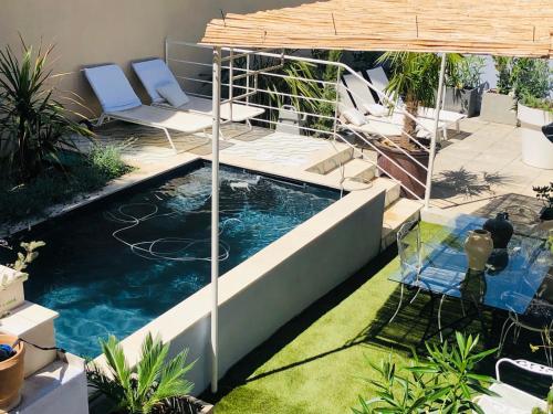 uma piscina num quintal com cadeiras e um guarda-sol em une maison bleue em Piolenc