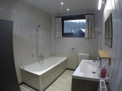 La salle de bains blanche est pourvue d'une baignoire et d'un lavabo. dans l'établissement Chalet Balthazar, à Durbuy