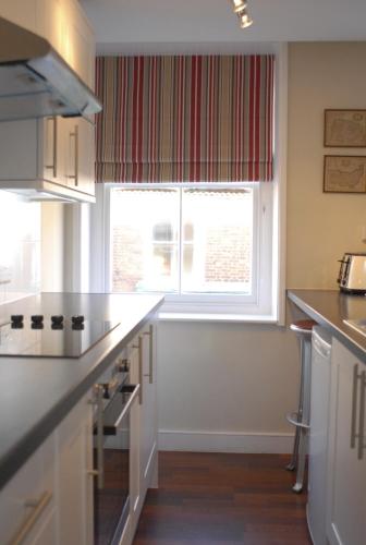 een keuken met witte werkbladen en een groot raam bij Short Stay Bungay in Bungay