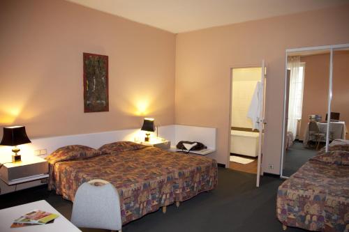 a hotel room with two beds and a mirror at Hôtel Au Pavillon du Frêne in Lacaune
