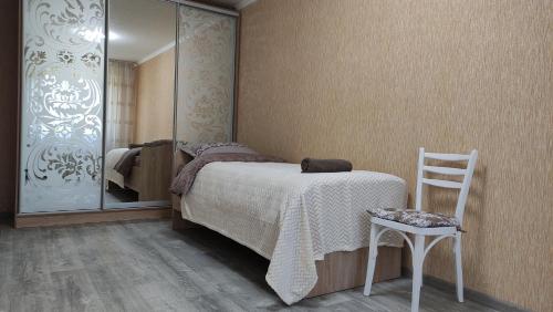 a bedroom with a bed and a chair and a mirror at Центр міста Грузинський 23,City Rooms in Bila Tserkva