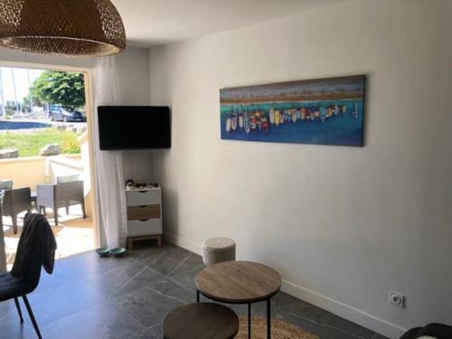 uma sala de estar com uma mesa e um quadro na parede em Appartement cosy à Boyardville em Boyard-Ville