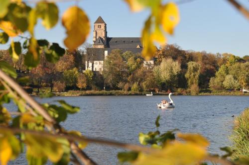 a group of people in a boat on a lake with a castle at Seaside Residenz Hotel Chemnitz in Chemnitz