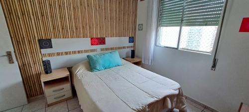 ein Schlafzimmer mit einem Bett mit einem blauen Kissen darauf in der Unterkunft Ap Vista do mar - Praia das Pitangueiras in Guarujá