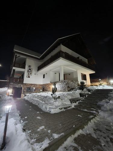 a building with snow in front of it at night at Agropensiunea turistică La Rusu in Rodna