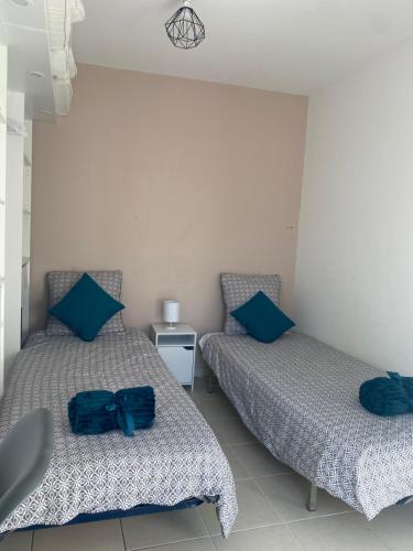 - 2 lits avec des oreillers bleus dans une chambre dans l'établissement Proche mer 3P+40m2 terrasse, à Antibes