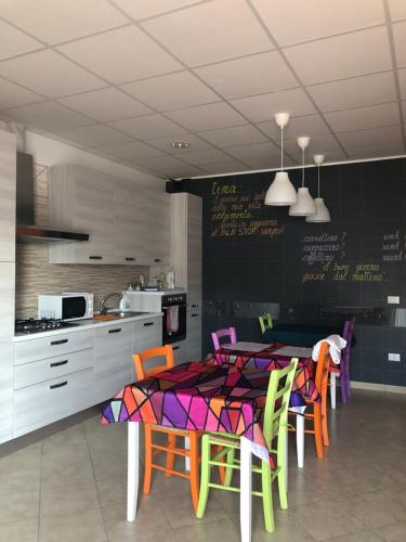 una cocina con una mesa con sillas coloridas y una pizarra en B&B Sangro, en Atessa