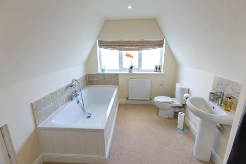 a bathroom with a tub and a toilet and a sink at Luxury 5 bedroom house - sleeps 10 in Colkirk