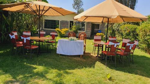 eine Gruppe von Tischen und Stühlen unter Sonnenschirmen in der Unterkunft Homebase gardens in Nakuru