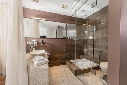 a bathroom with a shower and a toilet and a sink at Hotel Villa Lago Garni in Bad Wiessee