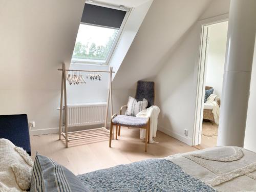 a bedroom with a bed and a window and a chair at Boende med pool och tennisbana i familjevänligt område in Torekov