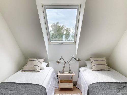 two beds in a room with a window at Boende med pool och tennisbana i familjevänligt område in Torekov