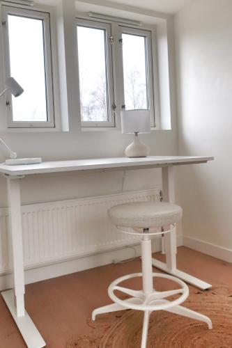 a white desk with a chair and two windows at Boende med pool och tennisbana i familjevänligt område in Torekov